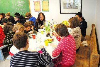 Mennsker sitter rundt et bord og spiser skolemat.