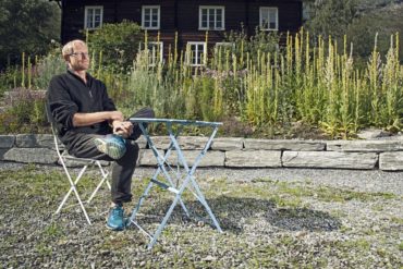 Ola Aukrust sitter på en stol i urtehagen