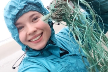 Jente plukker plastikk på strand