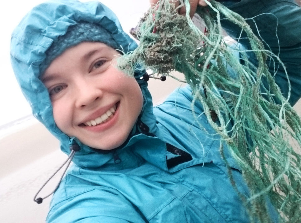 Jente plukker plastikk på strand