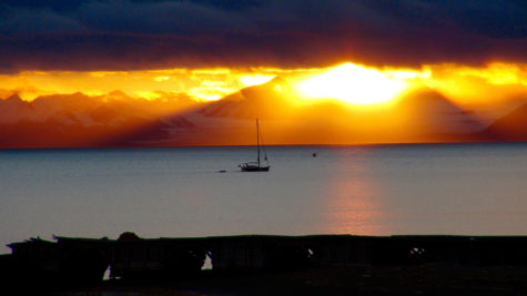 Solnedgang over hav med seilbåt