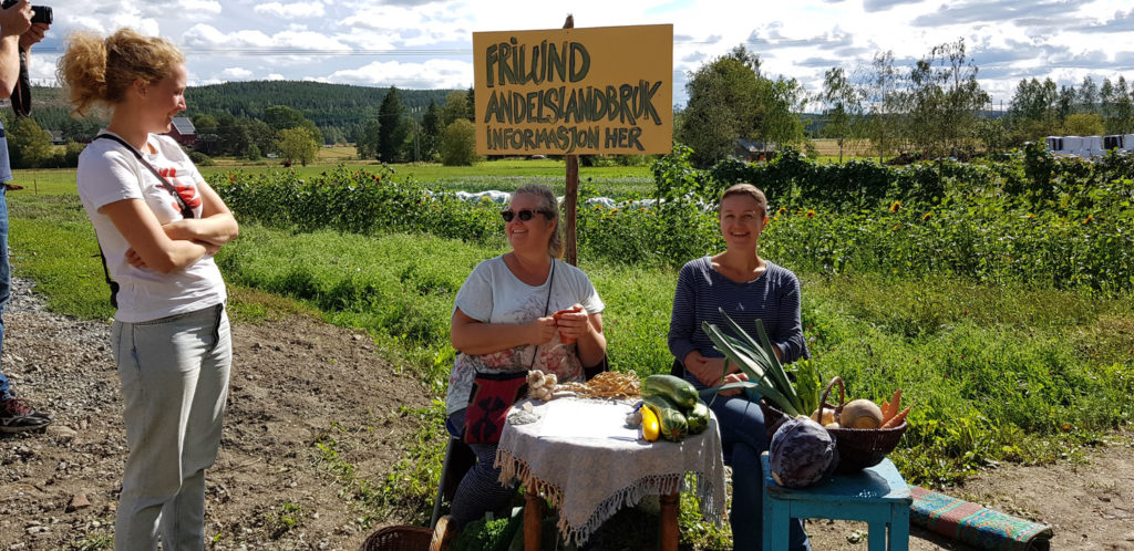 Mennesker sitter ved skilt som inviterer til låvekonsert