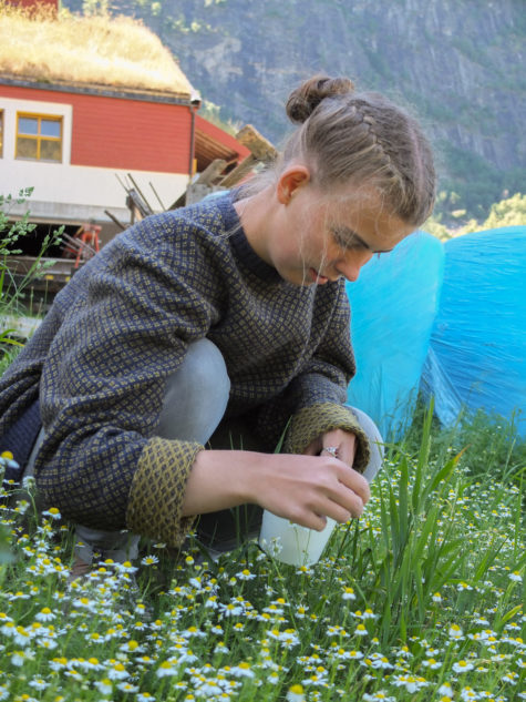 Kvinne sitter på huk i blomstereng