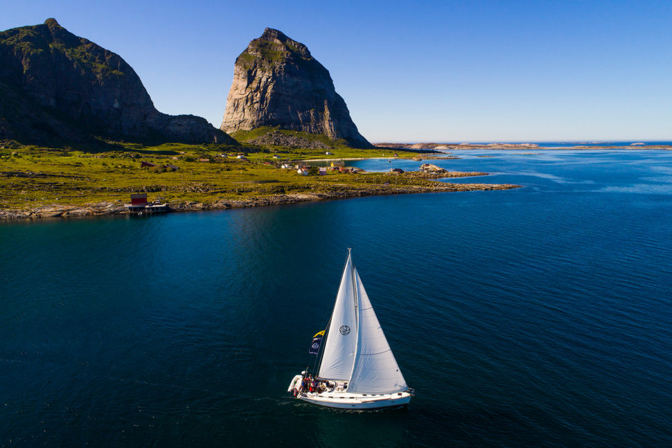 En seilbåt på havet med landskap i bakgrunnen