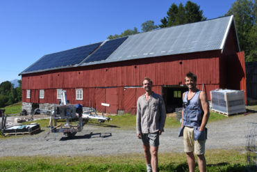 To menn ved driftsbygg med solcellepaneler på taket.