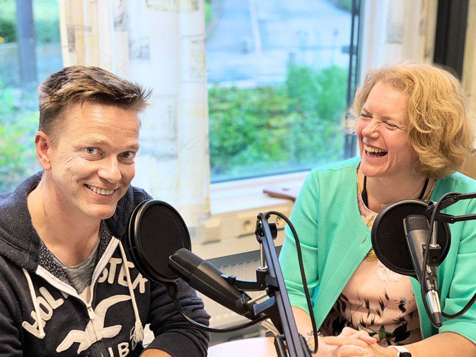 Mann og kvinne i radiostudio ler sammen.