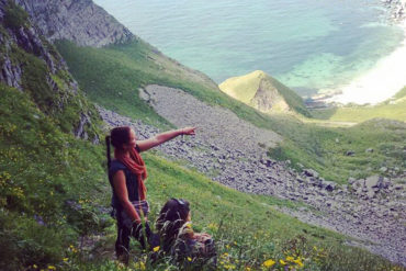 Kvinner i fjelllandskap peker mot havet i bakgrunnen