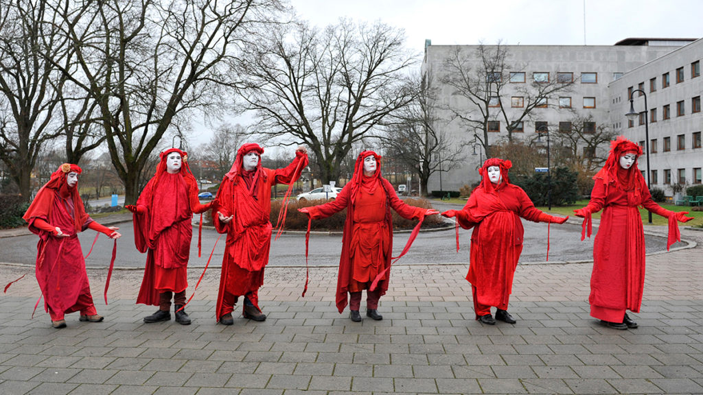 Aktivister i røde drakter utenfor bygning