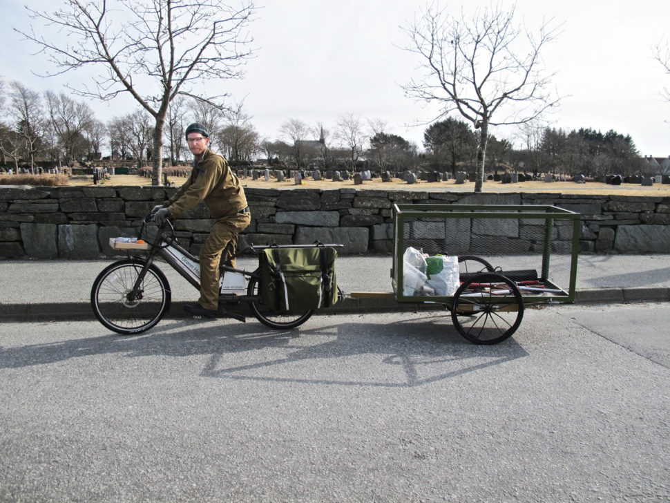 Mann på varesykkel passerer kirkegård.