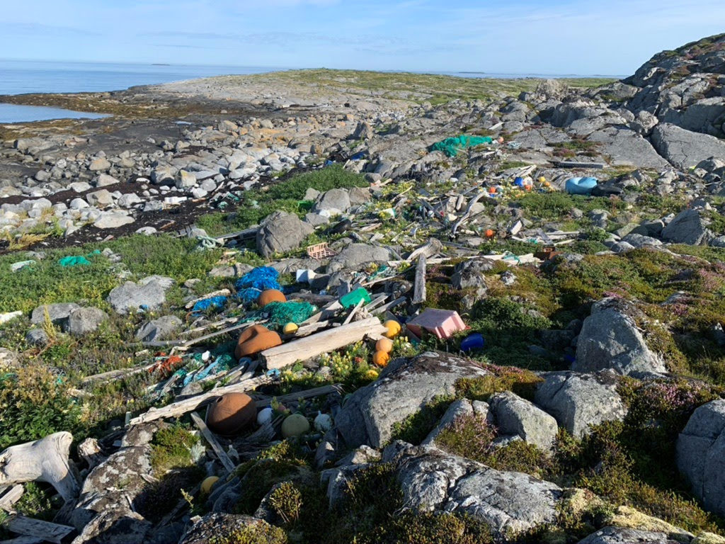 Forsøplet strand i nordlandslandskap