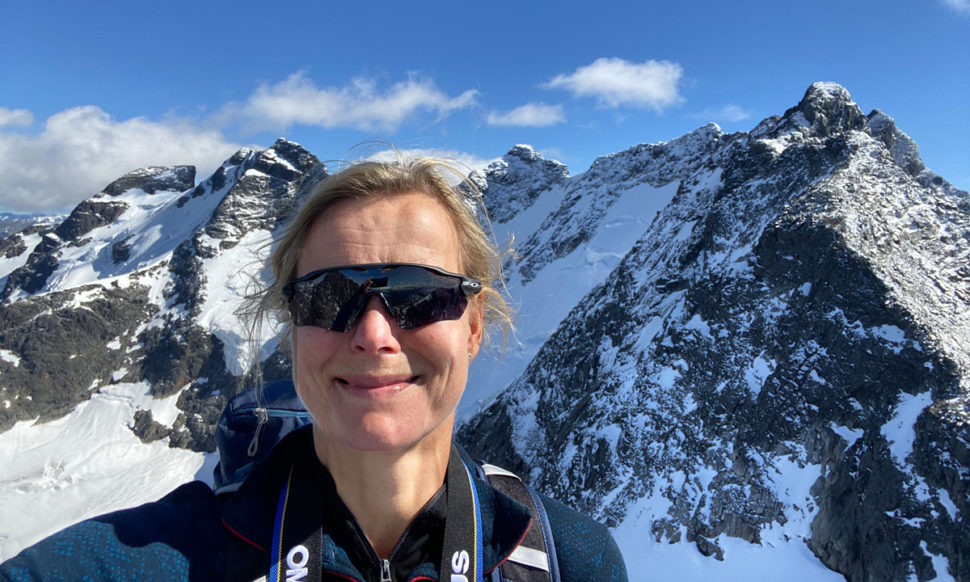 Kvinne med snøkledde fjell i bakgrunnen.