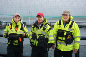 Tre mennesker i arbeidstøy på ved havet