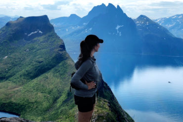 Kvinne i fjellområde ser ut over fjord.