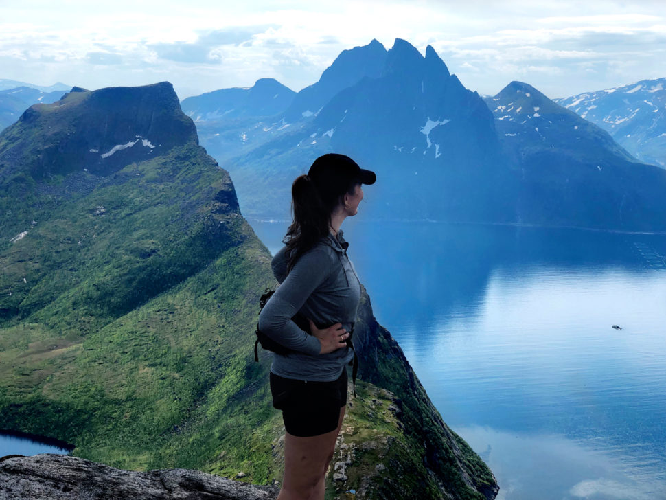 Kvinne i fjellområde ser ut over fjord.