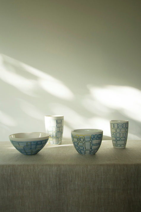 Spredt sollys fra vindu skinner over keramikkgjenstander på bord.