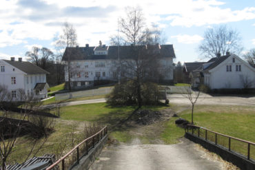 Gårdstun i landlige omgivelser med gårdsvei i forkant.