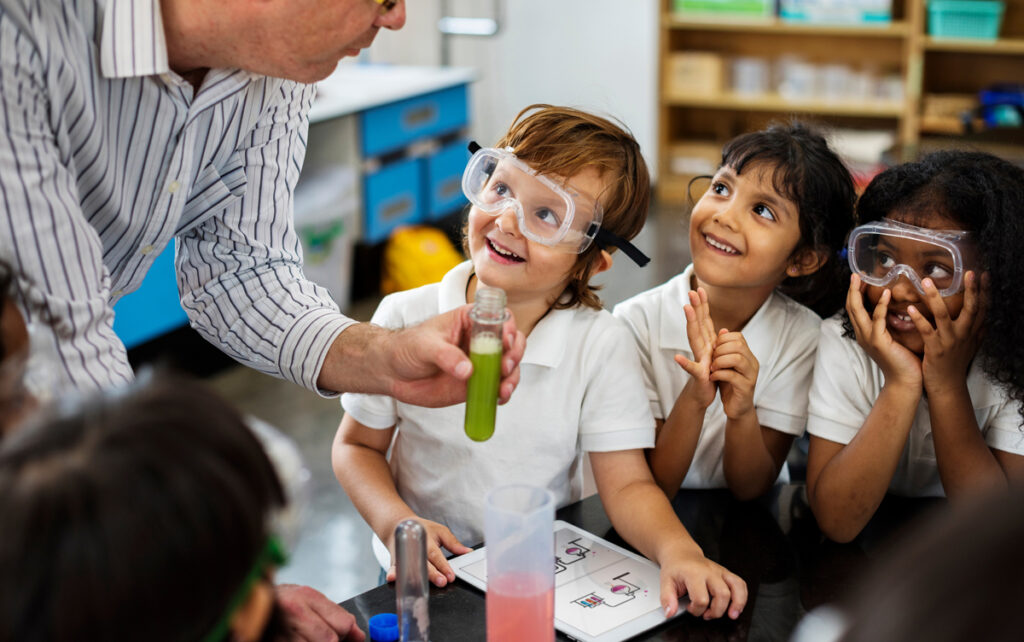 Barn studerer lærer med kjemisett