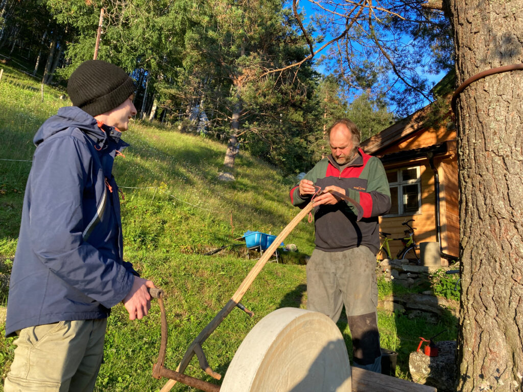 Mennesker foran utendørs slipestein i grønne omgivelser.