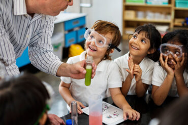 To barn ved siden av en voksen som viser et forskningseksperiment.