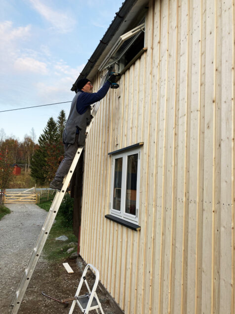 Person på stige støttet mot husvvegg