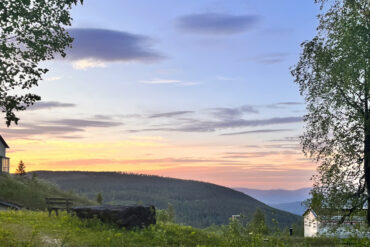 Gård i fjellandskap og kveldslys.