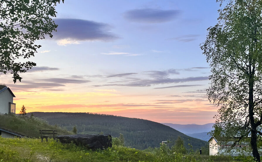 Gård i fjellandskap og kveldslys.