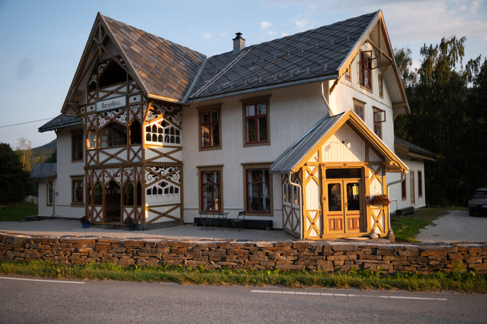 Gammel, hvit trebygning i kveldssol.