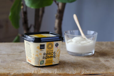 Bord med en pakke rømme og et glass med pakkens innhold ved siden av.