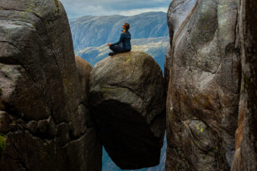 Person på stein kilt fast mellom to fjellvegger.