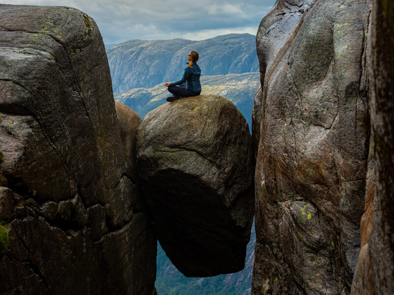 Person på stein kilt fast mellom to fjellvegger.