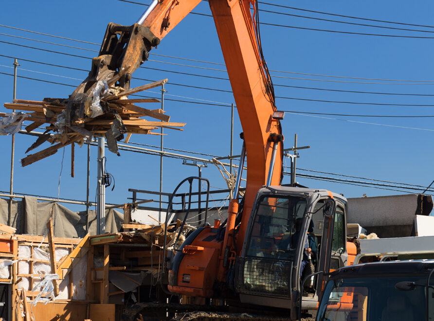 Gravemaskin løfter rester av bygning.